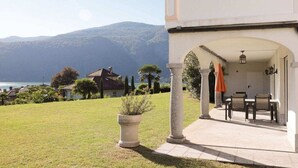A property with a patio area, outdoor seating, and a view of the sea and mountains. - Casa dell' Orso || Morcote (Morcote)
