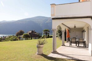 A property with a patio area, outdoor seating, and a view of the sea and mountains. - Casa dell' Orso || Morcote (Morcote)