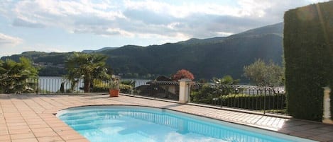 A swimming pool with a view of mountains and a fenced area with plants.