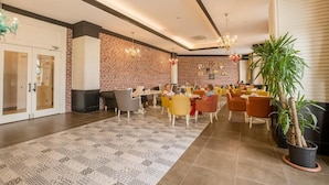 A lobby with a patterned carpet, brick wall, and seating area with chairs and tables. - J'adore Deluxe Hotel & Spa All Inclusive (Manavgat)