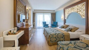 A hotel room with a bed, two armchairs, a small table, a desk, and a large mirror. - J'adore Deluxe Hotel & Spa All Inclusive (Manavgat)