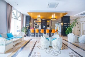 En hotellobby med barområde, siddepladser og et stort vindue.
