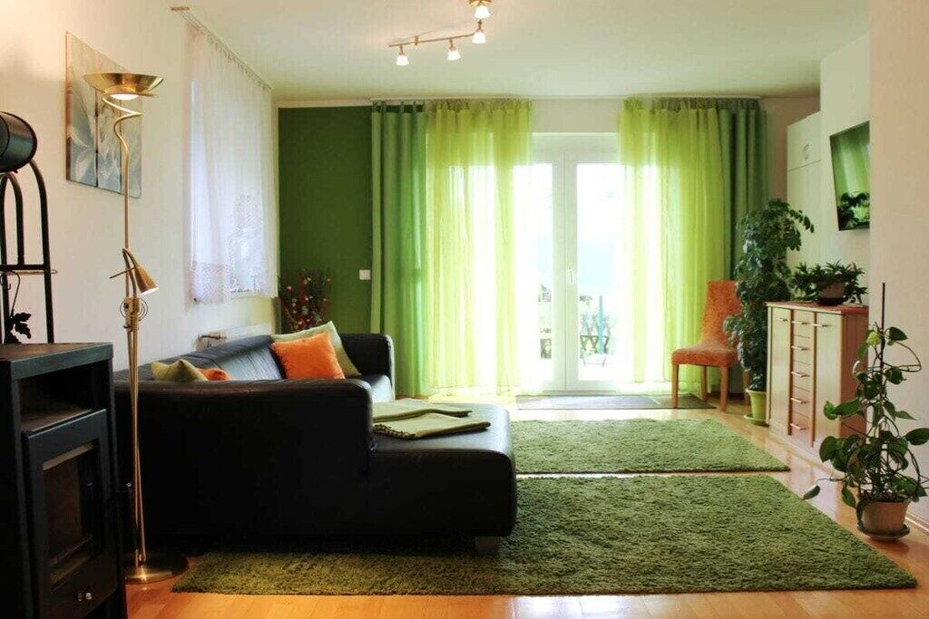 Una sala de estar con un sofá, una lámpara de pie, un televisor y una alfombra verde.