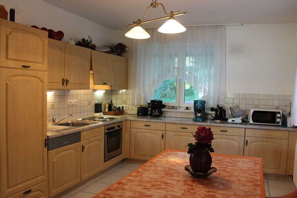 Una cocina con armarios de madera, un fregadero, una estufa, un microondas y un florero con flores en la isla.