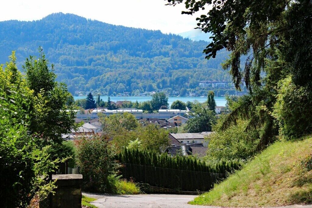 Un quartier résidentiel avec des maisons, un sentier et une vue sur un lac et des collines boisées au loin.