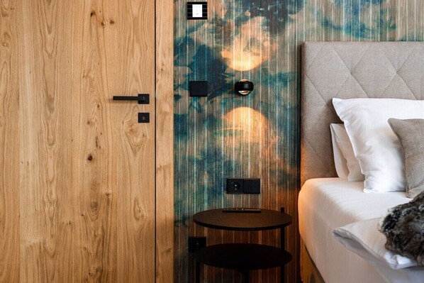A bedroom with a wooden wardrobe, a bed with white bedding, and a small round table.