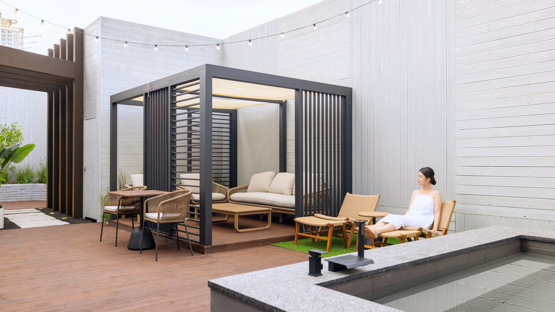 An outdoor seating area with a covered section, wicker furniture, and a person seated.