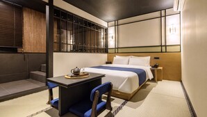 Habitación de hotel con cama, mesita de noche, silla y vistas al exterior.