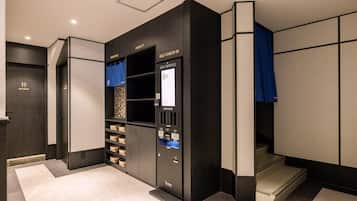 A hotel room with a self-service check-in kiosk, a minibar, and a view of the hallway.