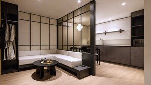 Un interior moderno con un sofá modular, una mesa de centro redonda, una zona de comedor y una kitchenette.