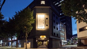 Entrada de un hotel con un letrero que muestra el nombre 'Ryokan Ryokan Hotel' y una entrada tradicional japonesa.