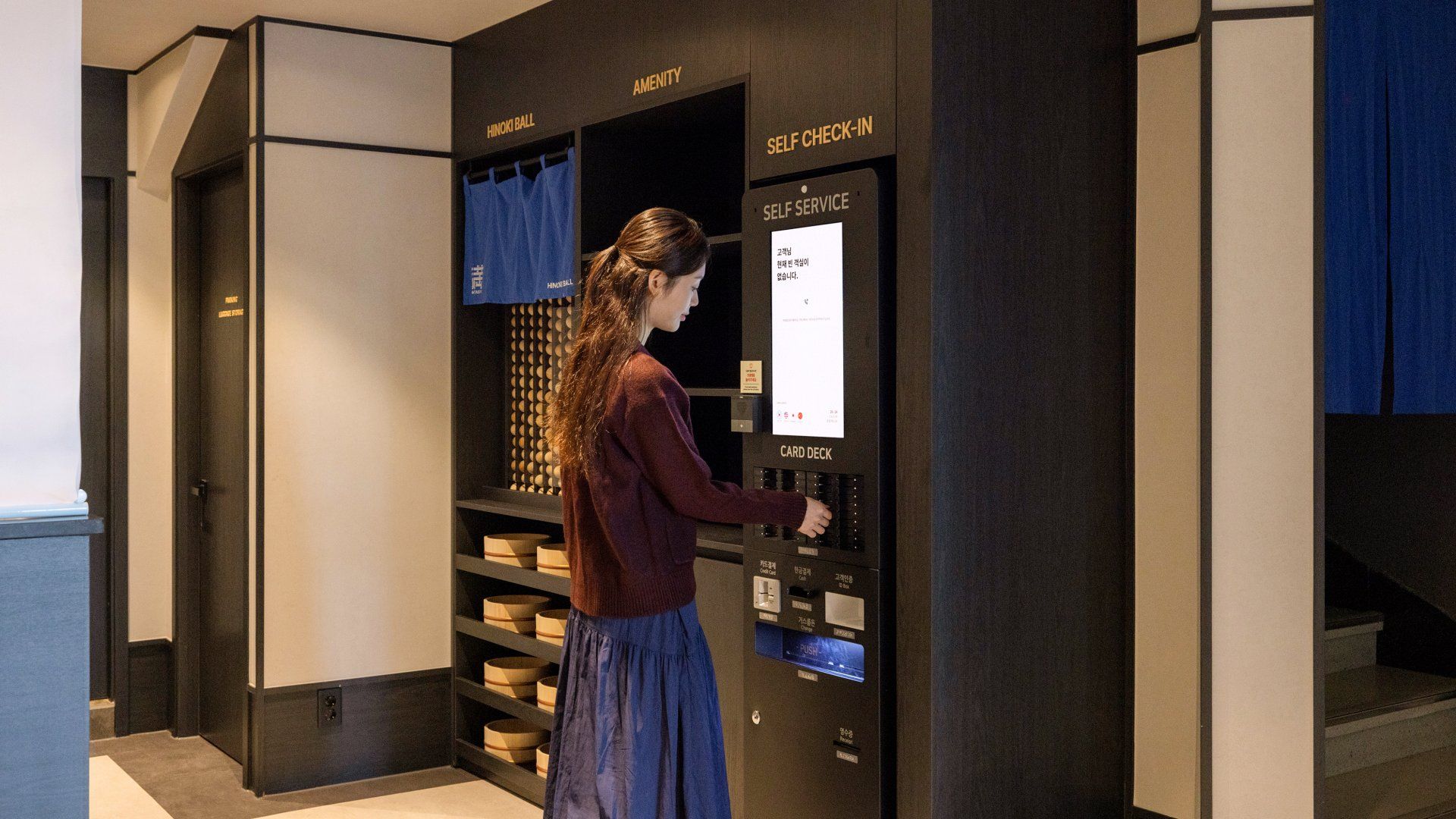 Una mujer interactuando con un terminal de tarjetas de autoservicio en el vestíbulo de un hotel.