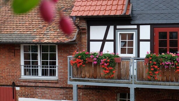 A traditional building with a tiled roof, wooden balcony railings, and flower boxes. - Holiday apartment with 1 bedroom (Milda, Deutschland)