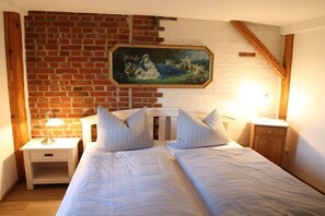 Une chambre avec deux lits, une table de chevet, une tête de lit en bois, un mur en briques et un tableau encadré.