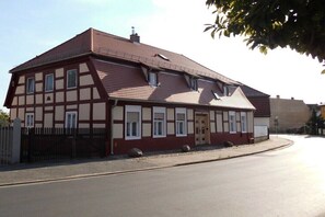 Un bâtiment à deux étages, doté d’une façade symétrique, d’un toit en pente et d’une cheminée visible.