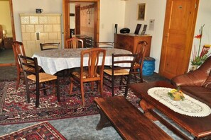 Un coin repas avec une table ronde, des chaises et un banc. On y trouve également un canapé et une petite table sur laquelle est posé un objet décoratif.