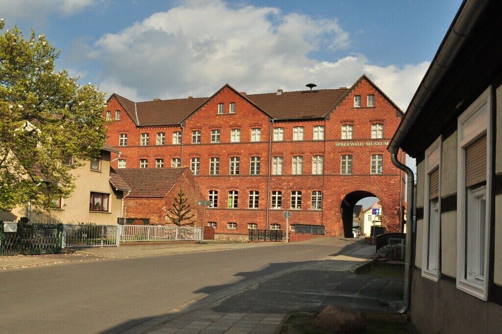 A red brick building with multiple windows and an archway entrance, likely a museum or public building.