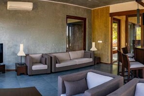 Una sala de estar con sofá, mesa de centro y televisor. Hay una puerta que conduce a otra habitación.