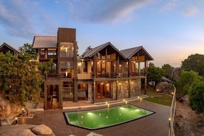 A multi-story building with a swimming pool, outdoor lighting, and a natural landscape.