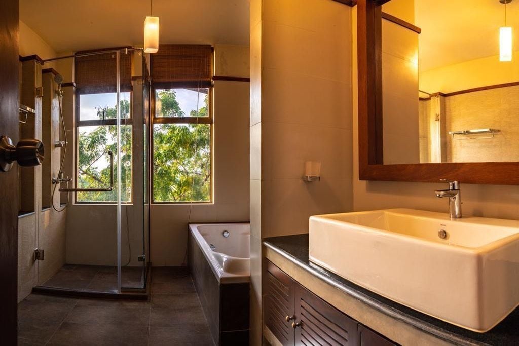 Un baño moderno con ducha envuelta en cristal, una bañera independiente y un amplio lavamanos con espejo.