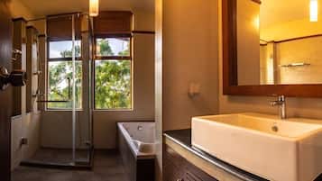 Un baño moderno con ducha envuelta en cristal, una bañera independiente y un amplio lavamanos con espejo.