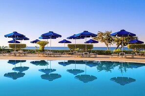A poolside area with lounge chairs and umbrellas, a clear sky, and a view of the sea. - Selia by James Hotel (Lardos)