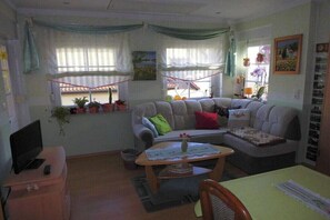A living room with a sofa, a coffee table, a TV, and a window with curtains. - In the Cucumber Quarter (Lübbenau\/Spreewald)