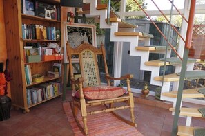 A room with a wooden bookshelf, a rattan chair, a staircase, and a window. - In the Cucumber Quarter (Lübbenau\/Spreewald)