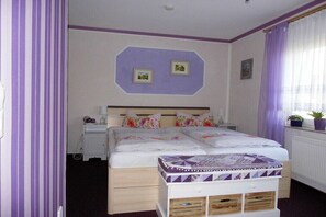 A bedroom with a bed, bedside tables, a window with curtains, and wall decorations. - In the Cucumber Quarter (Lübbenau\/Spreewald)