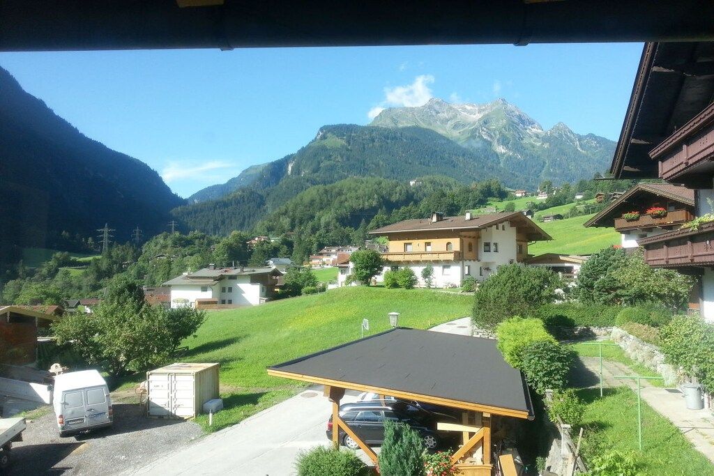 A rural village with houses, a car, and a mountain in the background.