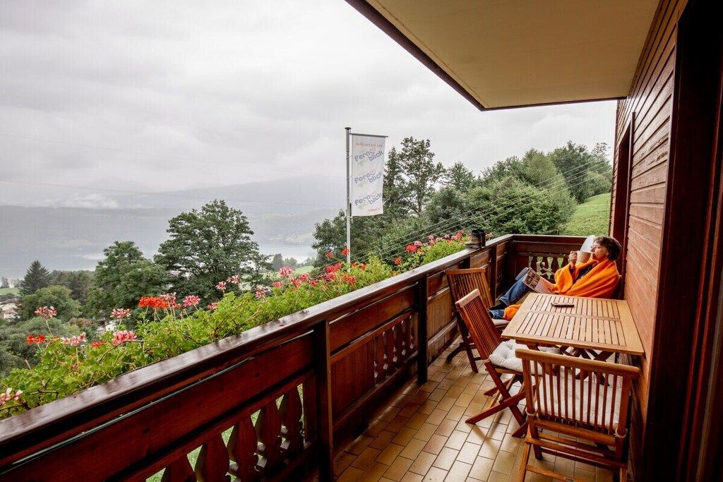 Een houten terras met een tafel en stoelen, met uitzicht op een mooi landschap met bloemen en bomen.