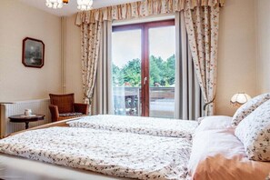 A bedroom with a double bed, a chair, a small table, and a view of the outdoors through a window with curtains. - "Rehsprung" in the Fernblick House (Millstatt)