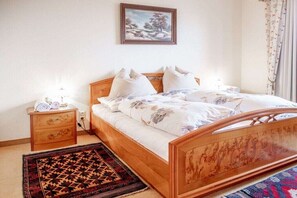 A bedroom with a wooden bed, a nightstand, a wall-mounted picture, and a patterned rug. - "Rehsprung" in the Fernblick House (Millstatt)