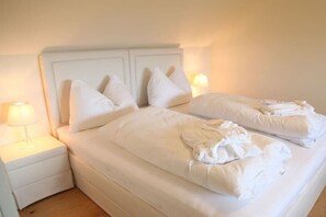 A twin bed with white bedding and pillows, a bedside table with a lamp, and a nightstand. - Holiday home with 1 bedroom (St.Johann im Saggautal)