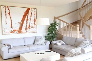 A living room with two sofas, a coffee table, a lamp, and a staircase. - Holiday home with 1 bedroom (St.Johann im Saggautal)