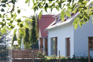 A white building with a red roof, a wooden deck, and a white lamp post. - Holiday home with 1 bedroom (St.Johann im Saggautal)