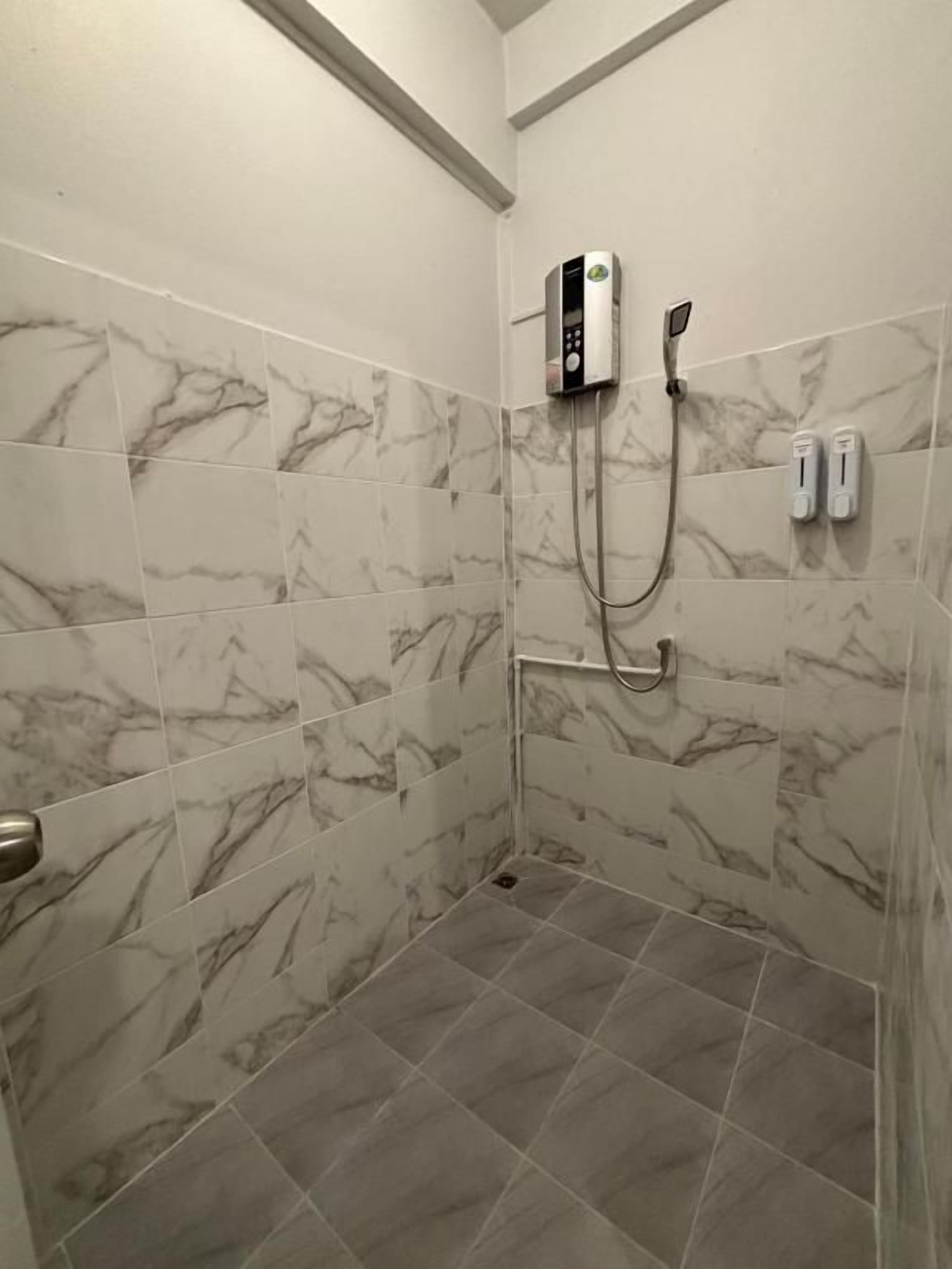 A shower with a handheld showerhead and a wall-mounted control panel.