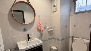 Un baño con lavamanos, espejo, inodoro y ventana.