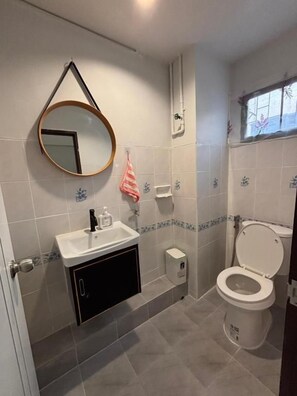 Ein Badezimmer mit Waschbecken, Spiegel, Toilette und Fenster.