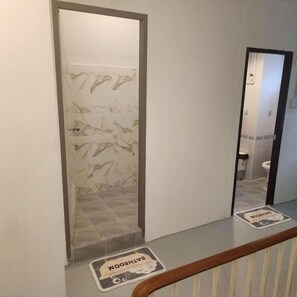 Un baño con pared de mármol, un inodoro y un espejo.
