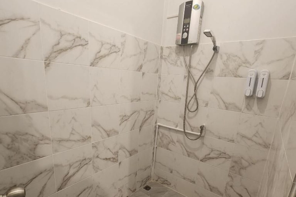 Un área de ducha con un cabezal de ducha de mano, un panel de control y un secador de manos.