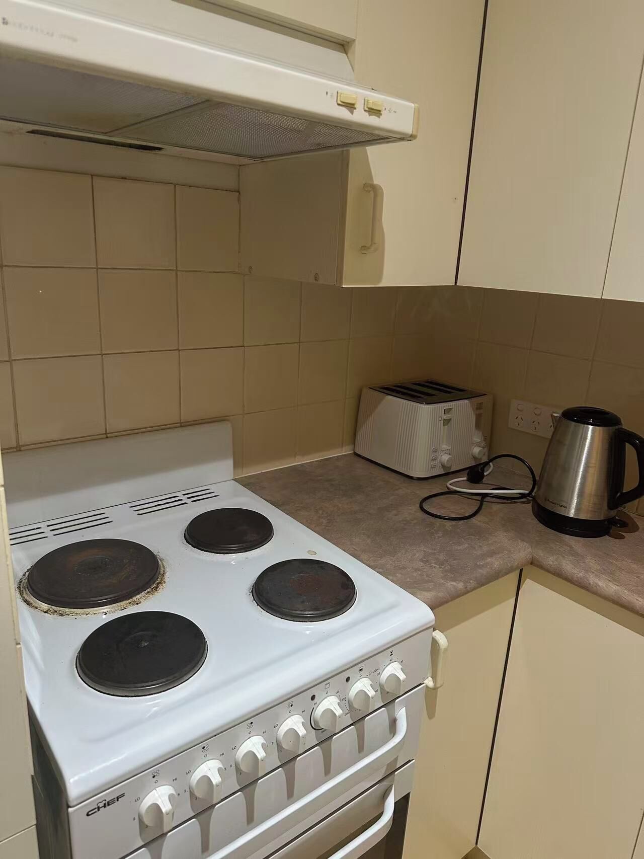Una cocina con estufa blanca, un tostador y una tetera.