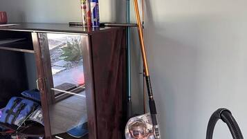 A room with a wooden cabinet, a vacuum cleaner, and fishing rods.