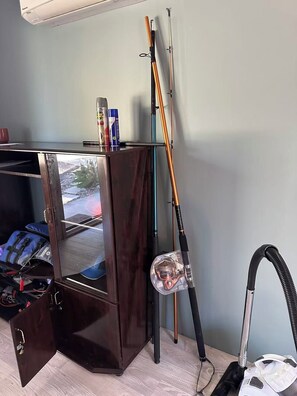 Ein Zimmer mit einem Holzschrank, einem Staubsauger und Angelruten.