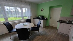 Cozinha compacta com mesa e cadeiras, micro-ondas e pia.