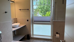A modern bathroom with a bathtub, a sink, and a shower. - Vrbo Property (Timmendorfer Strand)