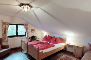 A bedroom with a wooden bed, a nightstand, a chair, a window with curtains, and a radiator. - Holiday apartment with 3 bedrooms (Patergassen)