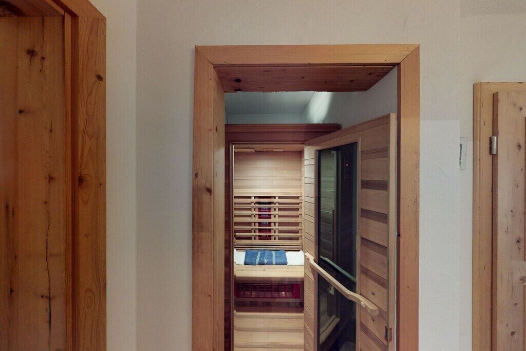 Un étroit couloir en bois, avec un escalier menant à une pièce dotée d’une grande fenêtre.