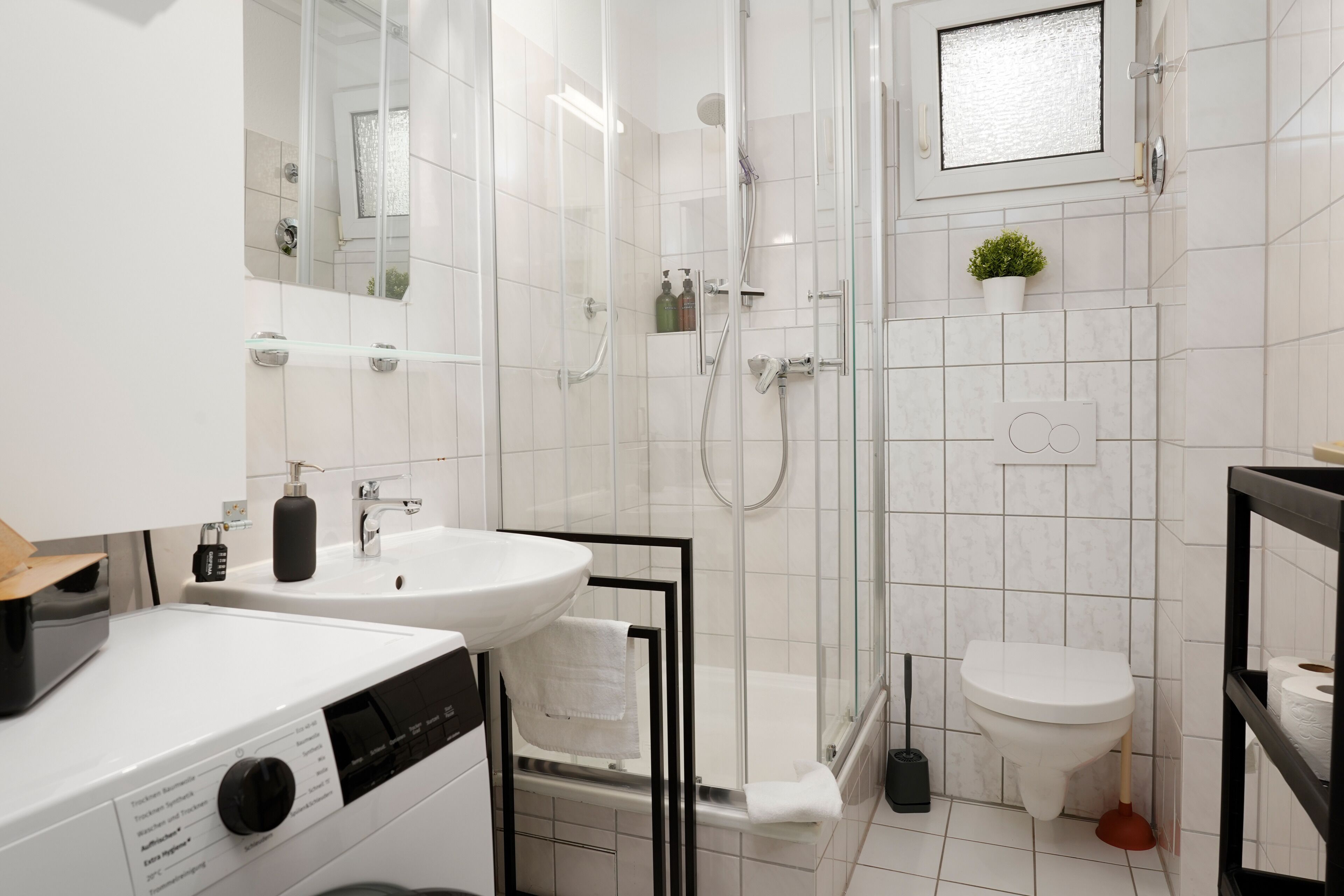 Ein modernes Badezimmer mit einer gläsernen Duschkabine, einem weißen Waschbecken und einer Toilette.