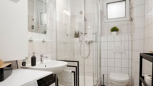 Een moderne badkamer met een douchecabine van glas, een wit wastafelmeubel en een toilet.
